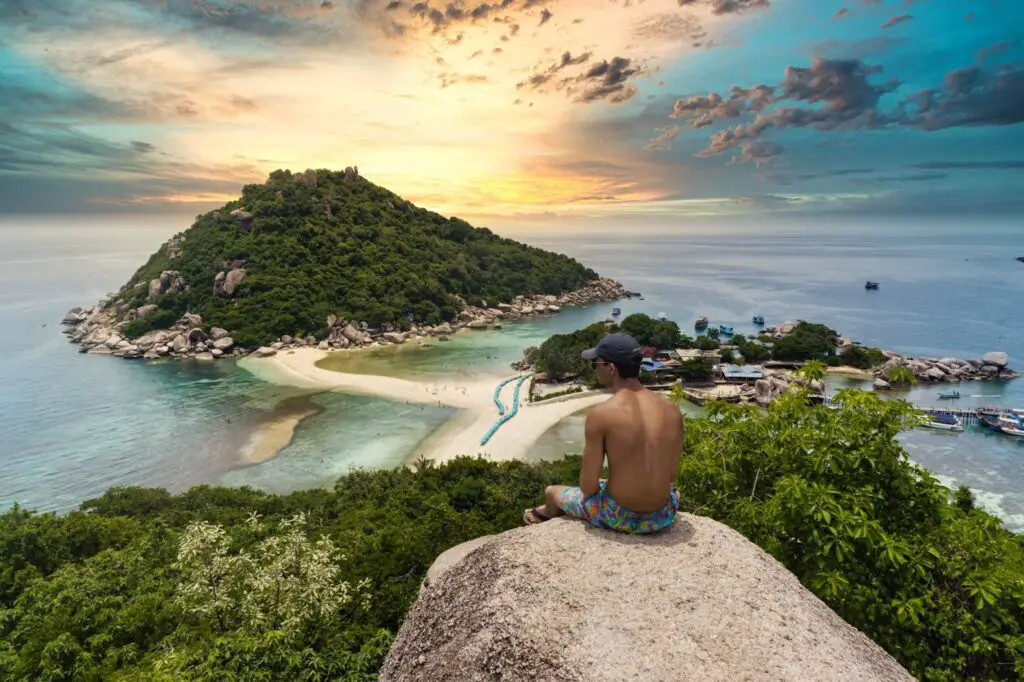 man sitting on a rock overlooking island
